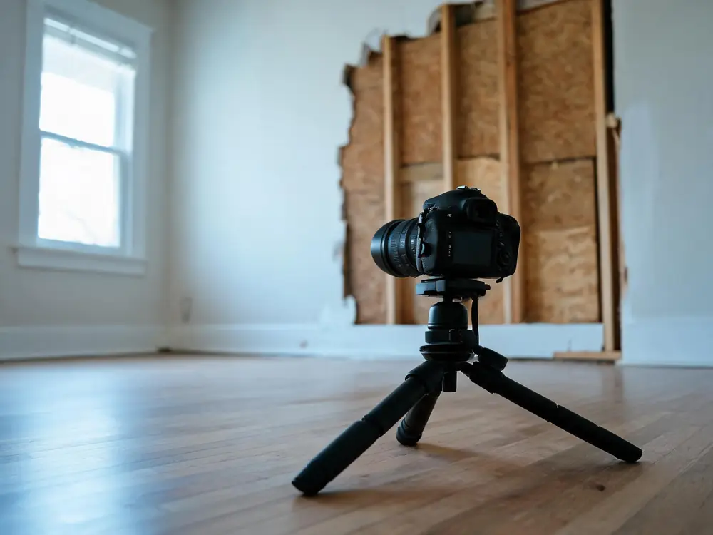 Camera on a tripod documenting a damaged wall