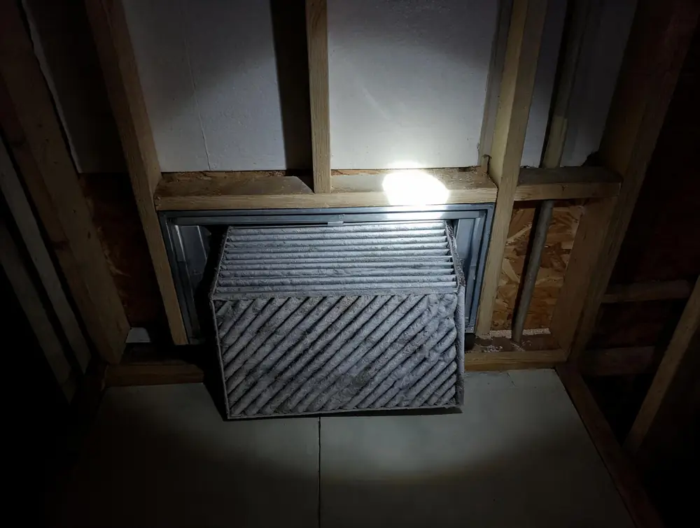 Dirty pleated furnace filter pulled from its slot