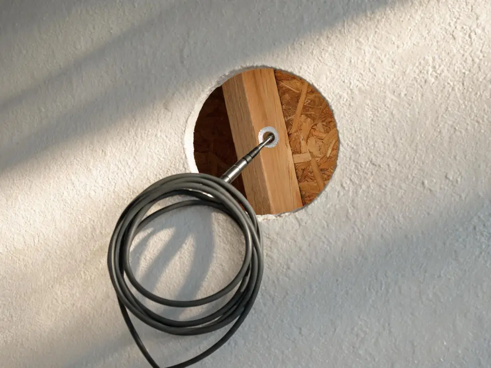 Borescope probe inserted through a small hole in drywall
