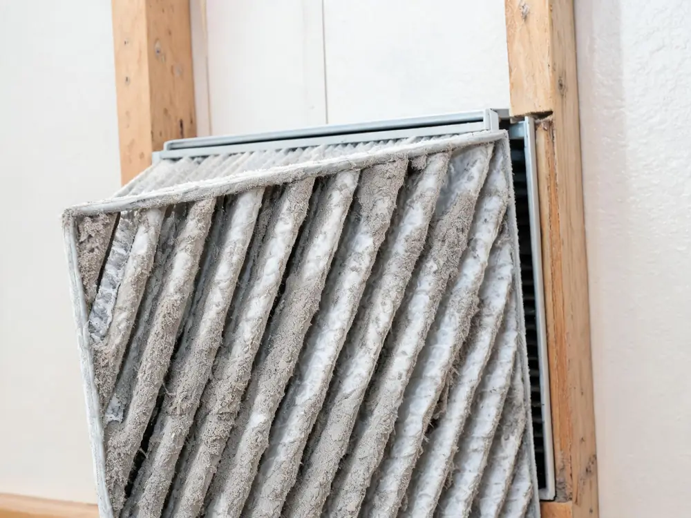 Dirty pleated furnace filter pulled from its slot