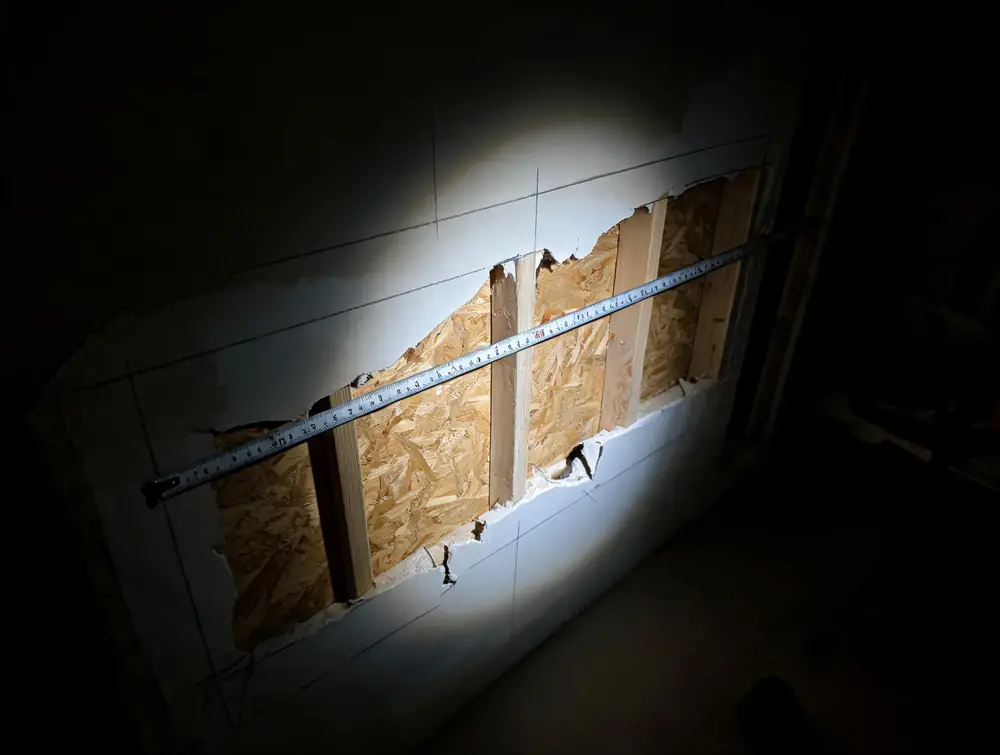 Tape measure pulled across a damaged wall section
