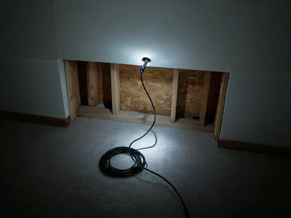 Borescope probe inserted through a small hole in drywall